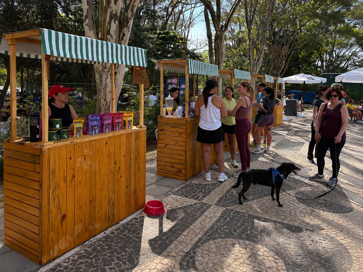 Estandes de madeira com toldo listrado verde e branco durante o evento na Orla